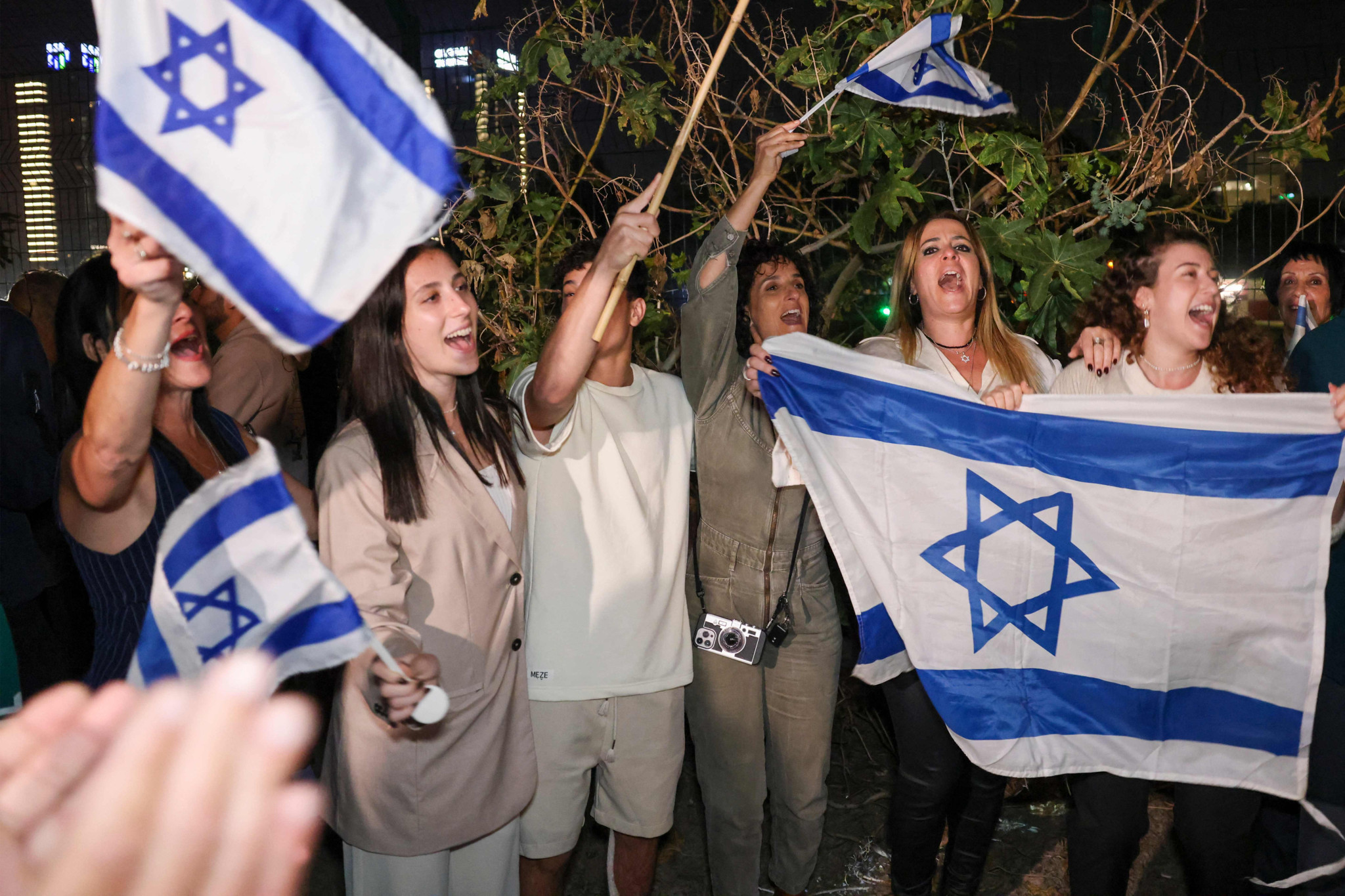 Israelis cheer as a Israeli helicopter with released hostages lands at Tel Aviv's Schneider medical centre on November 24, 2023. Hamas on November 24, freed a first batch of hostages seized in the deadliest attack in Israel's history under a deal that saw a temporary truce take hold in war-ravaged Gaza. Thirteen Israeli hostages captured during Palestinian militants' cross-border raids were back in Israeli territory where they would undergo medical checks before being reunited with their families, the army said. (Photo by JACK GUEZ / AFP)