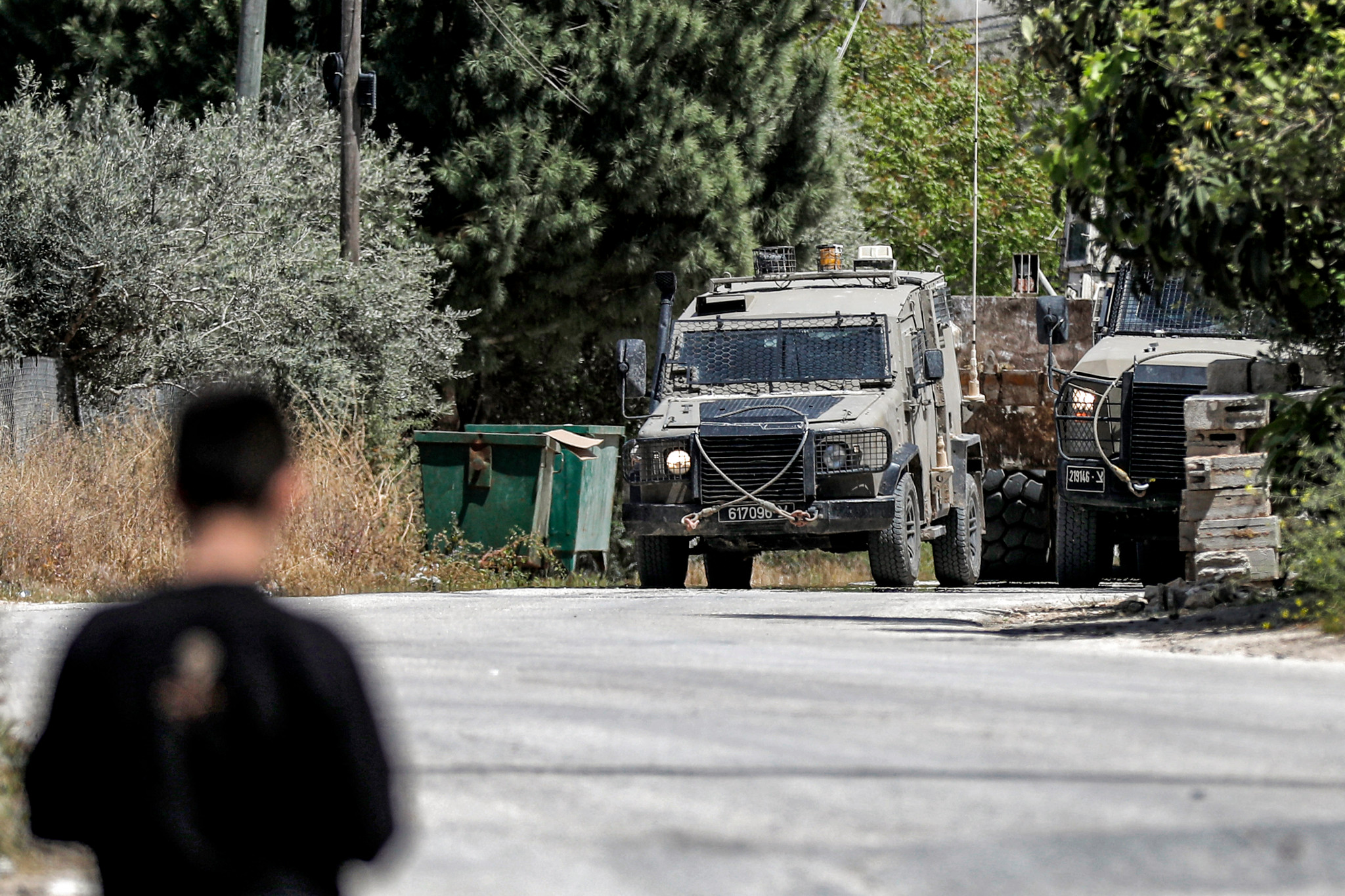 Un homme regarde des véhicules blindés militaires israéliens lors d’une opération à al-Misliyah, sud de Jénine, Cisjordanie occupée, le 16 avril 2025.