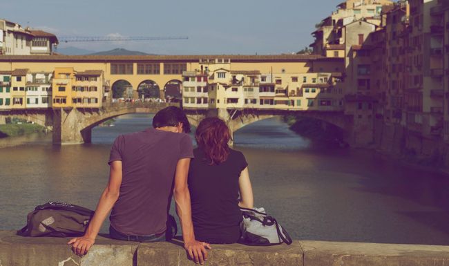 Frau und Mann sitzen vor einer Brücke.