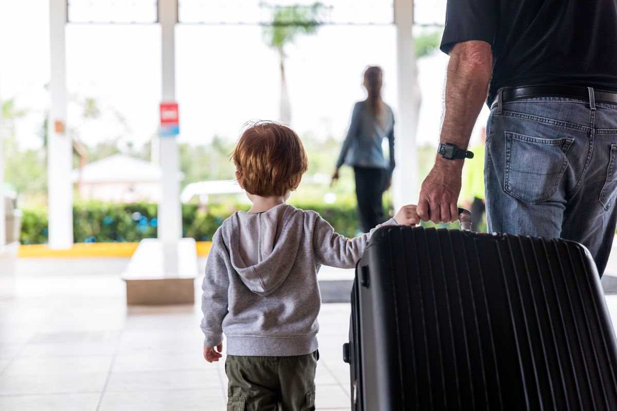 Father or Grand Father and Baby Boy walking in the airport or Hotel lobby with Suitcase