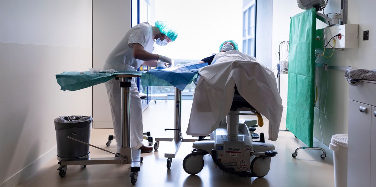 Deux professionnels de la santé en tenue stérile s'occupent d'un patient sur un brancard dans une salle de traitement d'urgence de l'hôpital de Triemli à Zurich, le 28 novembre 2018.