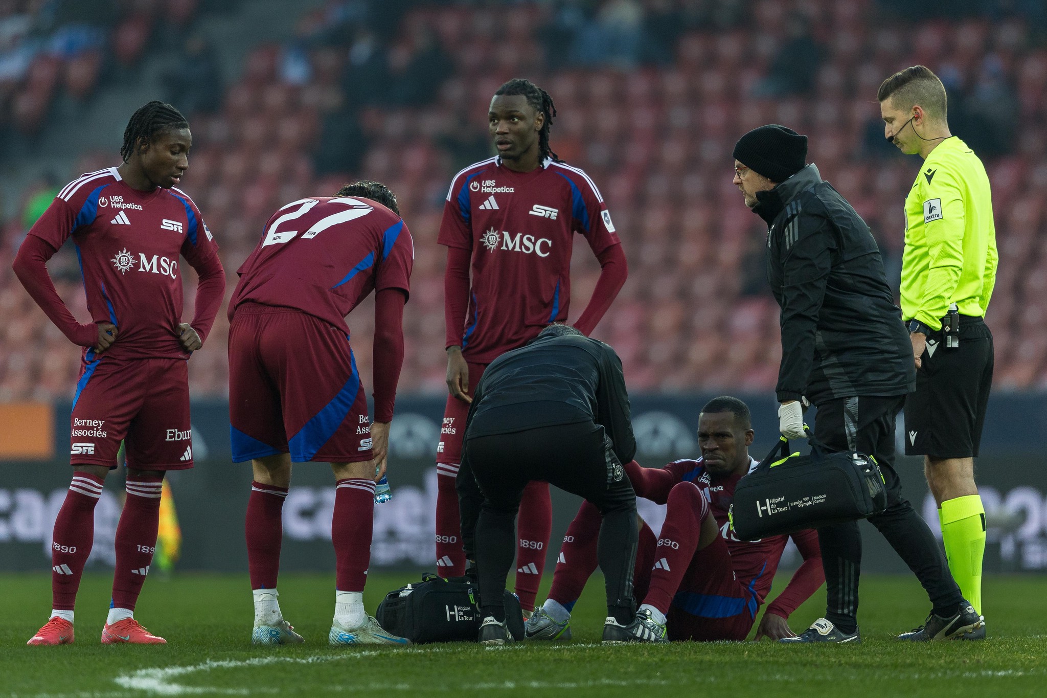 Joueurs du Servette FC, Tiemoko Ouattara, Enzo Crivelli, Joseph Nonge, entourant Dereck Kutesa blessé au sol, avec l’arbitre Luca Piccolo, lors du match contre GC Zurich en Super League, le 16 février 2025 à Zurich.