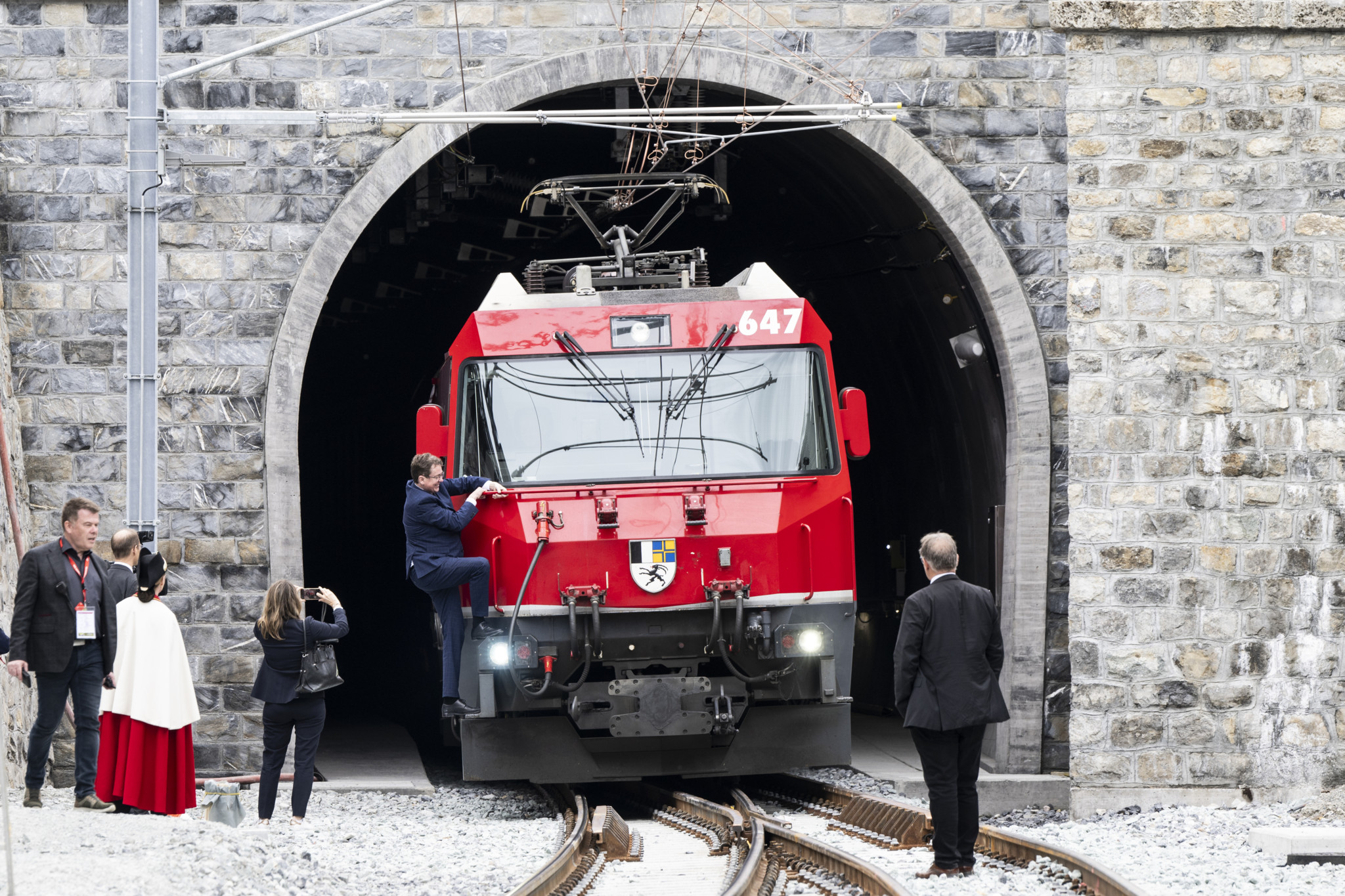 Bundesrat Albert Roesti klettert auf den Zug der Rhaetischen Bahn vor dem neuen Albulatunnel, bei der Eroeffnung des neuen Albulatunnels der Rhaetischen Bahn (RhB), am Samstag, 8. Juni 2024, in Spinas/Preda. Nach einer Bauzeit von 10 Jahren und mit Gesamtprojektkosten von 407 Millionen Franken wird der neue Tunnel den alten Albulatunnel ersetzen. (KEYSTONE/Mayk Wendt)