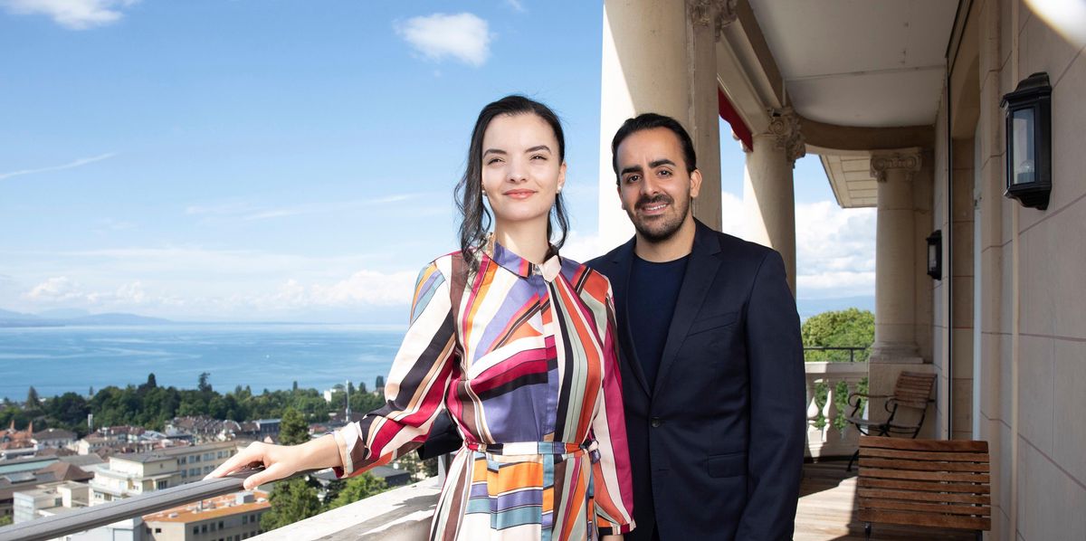 Franck Peux et Sarah Benahmed se tiennent sur le balcon du Lausanne Palace avec vue sur le lac Léman.