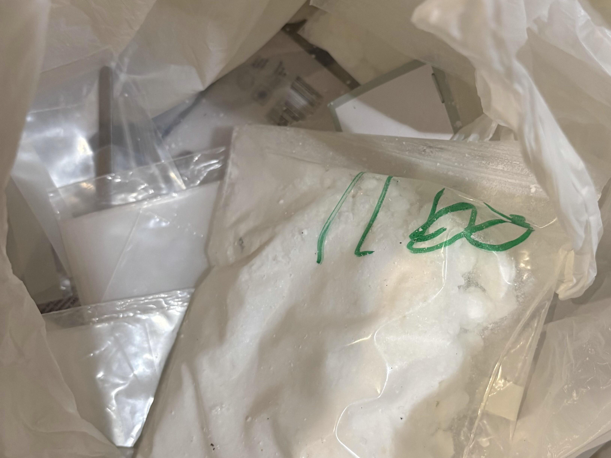 Plastiktüten mit weissem Pulver und grüner Schrift in einer grösseren Tüte.