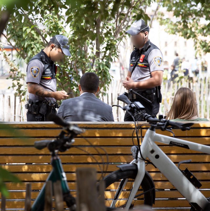 Deux agents de la Police Municipale de Genève verbalisent un individu sur un banc pour avoir jeté un mégot, le 16 août 2019.