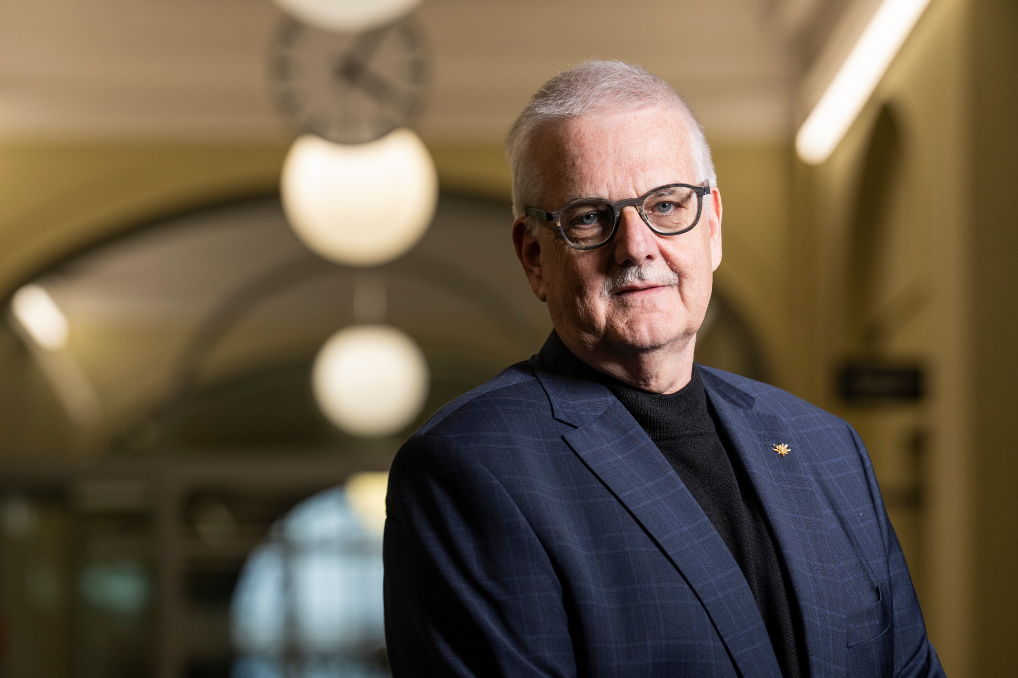 Alexander Ott, Chef der Fremdenpolizei Bern, in einem dunkelblauen Sakko mit Brille in einem Berner Gebäude mit gewölbten Decken.