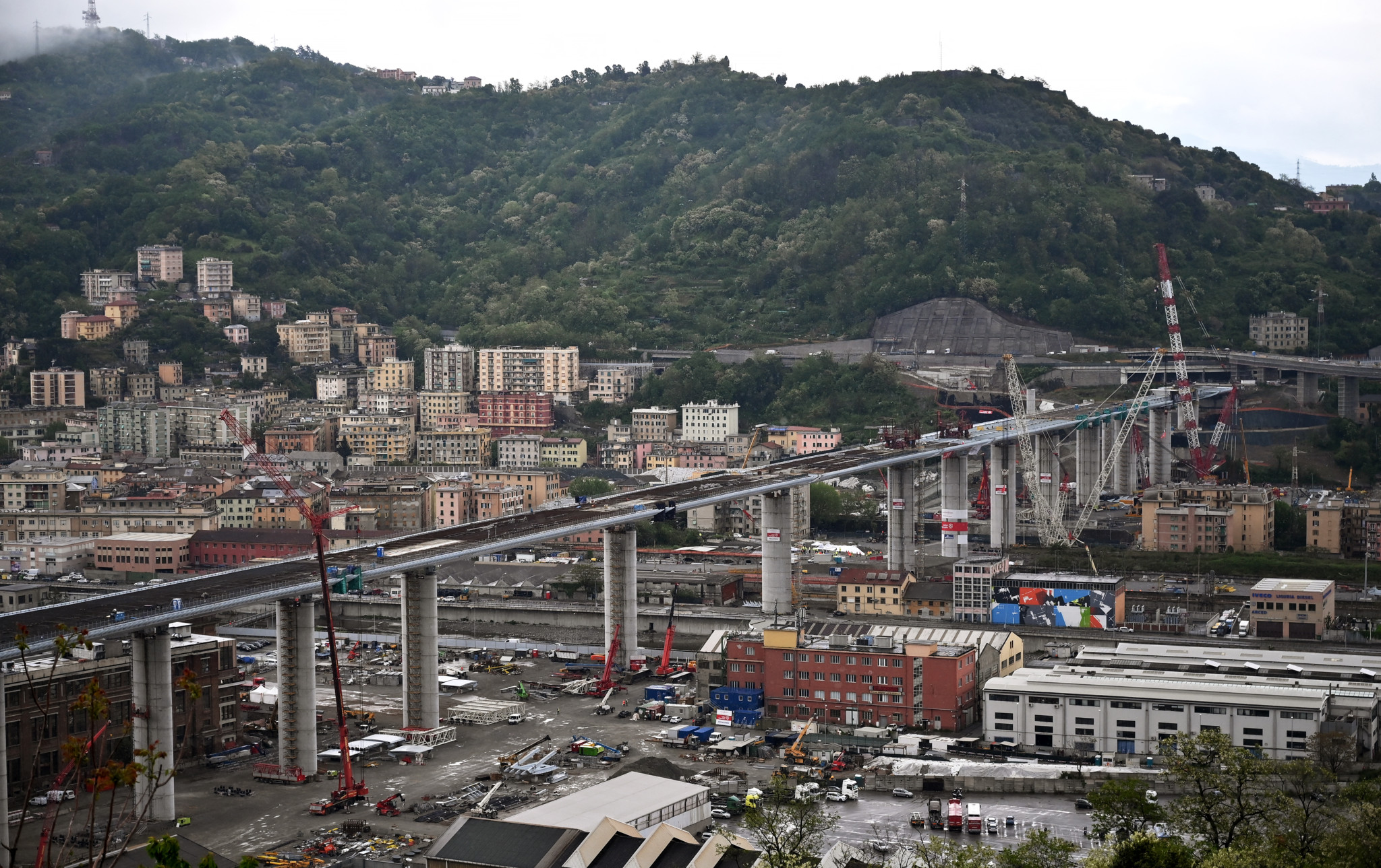 A general view shows the new Genoa bridge, as the last 44-meter long span has been almost completed hoisted between columns 10 and 11 (8th column from L) on the bridge's eastern side on April 28, 2020 in Genoa, during the country's lockdown aimed at curbing the spread of the COVID-19 infection, caused by the novel coronavirus. The hoist of the last span of the Genoa bridge is to be completed on April 28, 2020 to symbolically reunite the two sides of the valley. The bridge designed by Italian architect Renzo Piano, has been under construction without interruption since June 25, 2019, after the August 14, 2018 collapse of the Morandi viaduct that killed 43 people. (Photo by Marco BERTORELLO / AFP)
