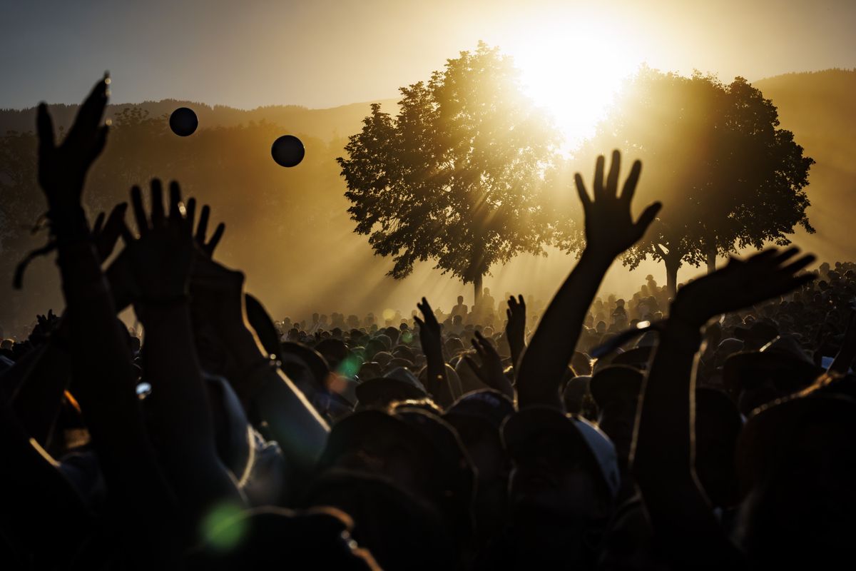 Festival goers cheers in front of the main stage, as dust from the dry ground is lifted in the air at sunset, during the 45th edition of the Paleo Festival, in Nyon, Switzerland, Sunday, July 24, 2022. The Paleo is the largest open-air music festival in the western part of Switzerland. (KEYSTONE/Valentin Flauraud)