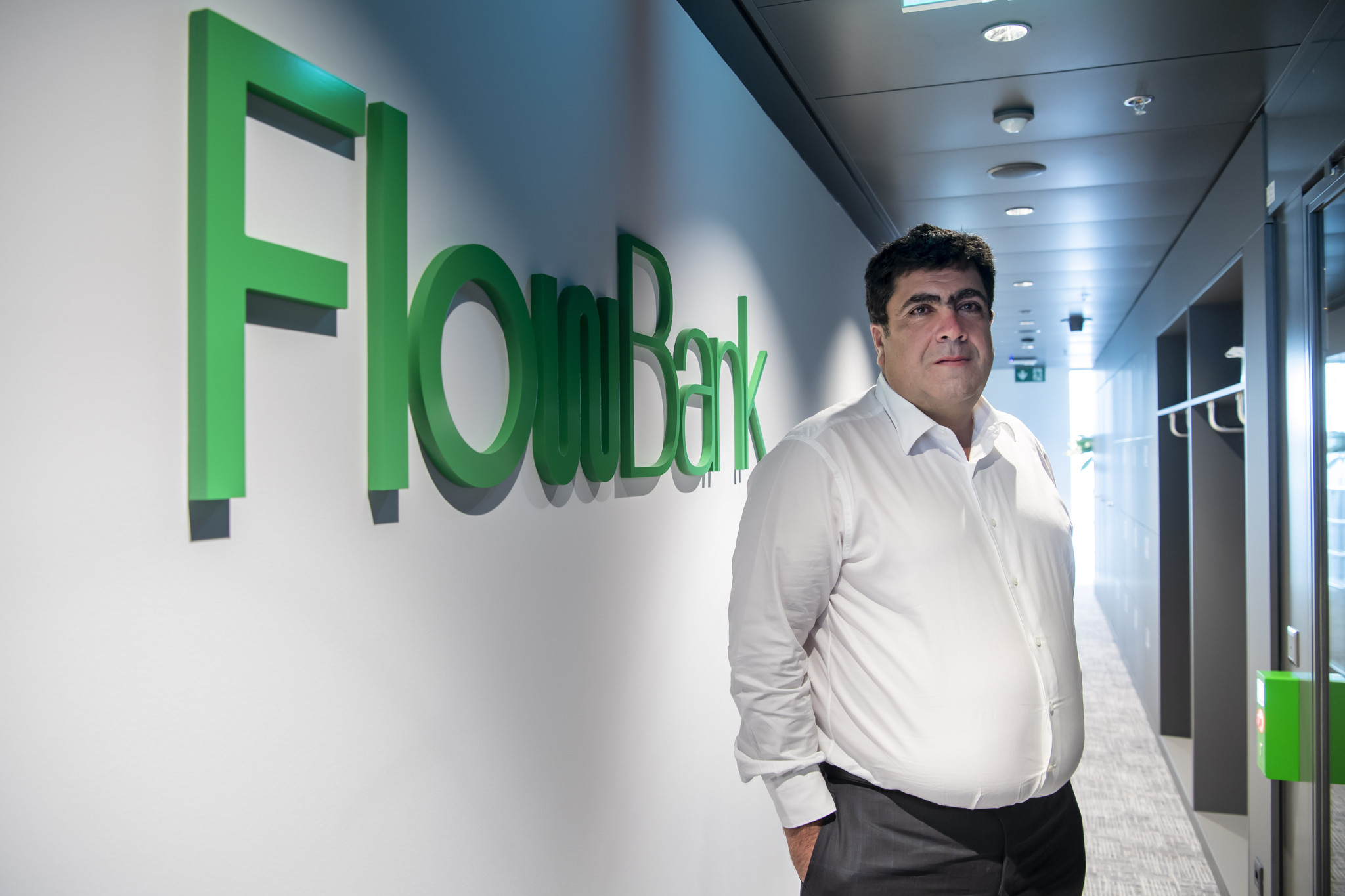 Charles-Henri Sabet, fondateur de la banque online Flowbank, pose a coter du logo de sa banque, ce mercredi 25 novembre 2020 a Geneve. FlowBank est une banque suisse specialisee dans les services en ligne. (KEYSTONE/Martial Trezzini)