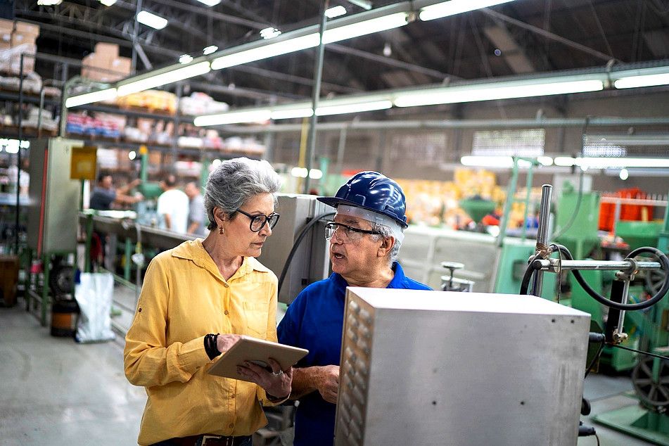 Manager and employee using equipment in a factory