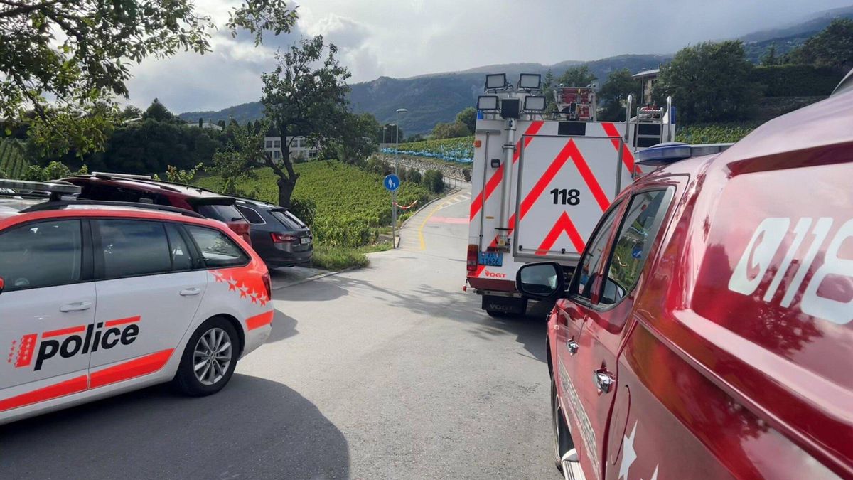 Des véhicules de police et d'incendie sont garés près de l'école CO de Goubing à Sierre, suite à une alerte à la bombe le 12 septembre 2024. Le site est entouré de collines et de végétation.