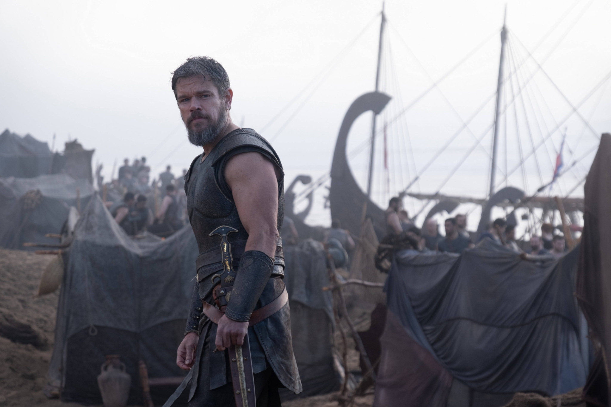 Matt Damon als Odysseus in Christopher Nolans «The Odyssey», in antiker Kriegsrüstung vor antiken Schiffen am Strand.
