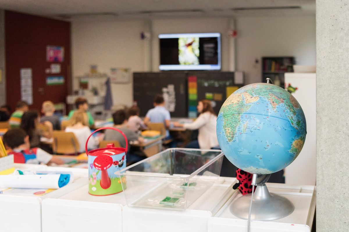 Une salle de classe à Schule Suhr avec un globe au premier plan et des élèves en train d’étudier à l’arrière-plan. Photo prise le 25 juin 2018.