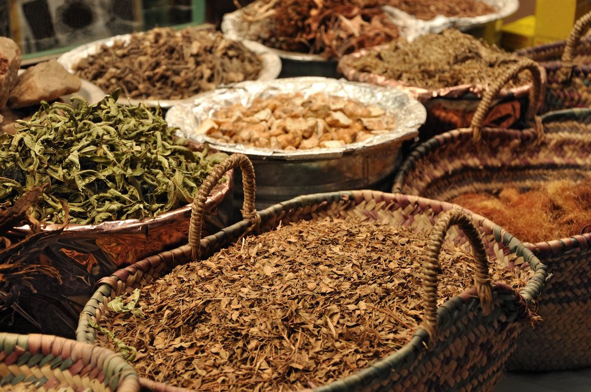 Herbes séchées dans un souk marocain, présentées dans des paniers et des plateaux tissés.