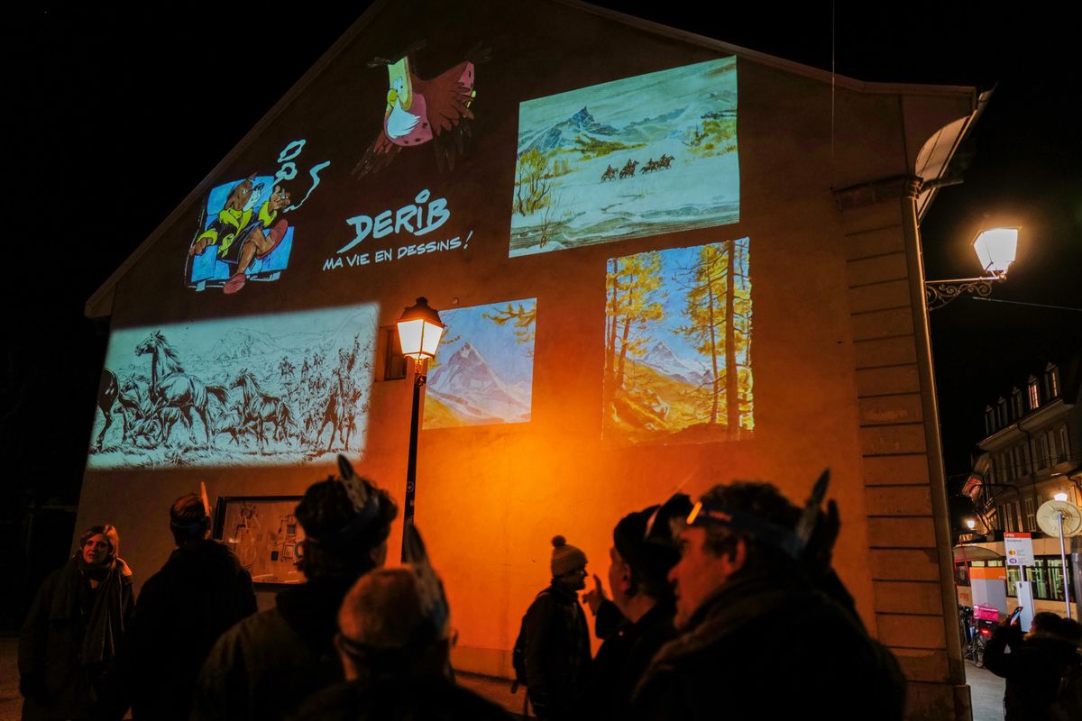 Genève 01/02/2024Déambulation à travers Carouge autour de l'œuvre de Derib. Des projections ont lieu sur certains murs, notamment sur la place du Marché, à l'église Sainte-Croix, à l'école des Pervenches et sur la façade de l'auberge communale.Des totems sont également illuminés, représentant des éléments récurrents dans l'œuvre de Derib.