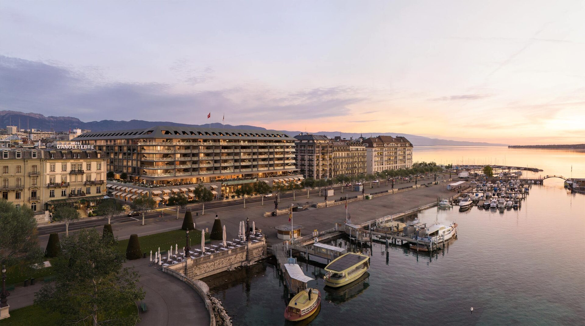 Vue panoramique du quai des Bergues à Genève au coucher du soleil, avec des bâtiments historiques et un port de plaisance.