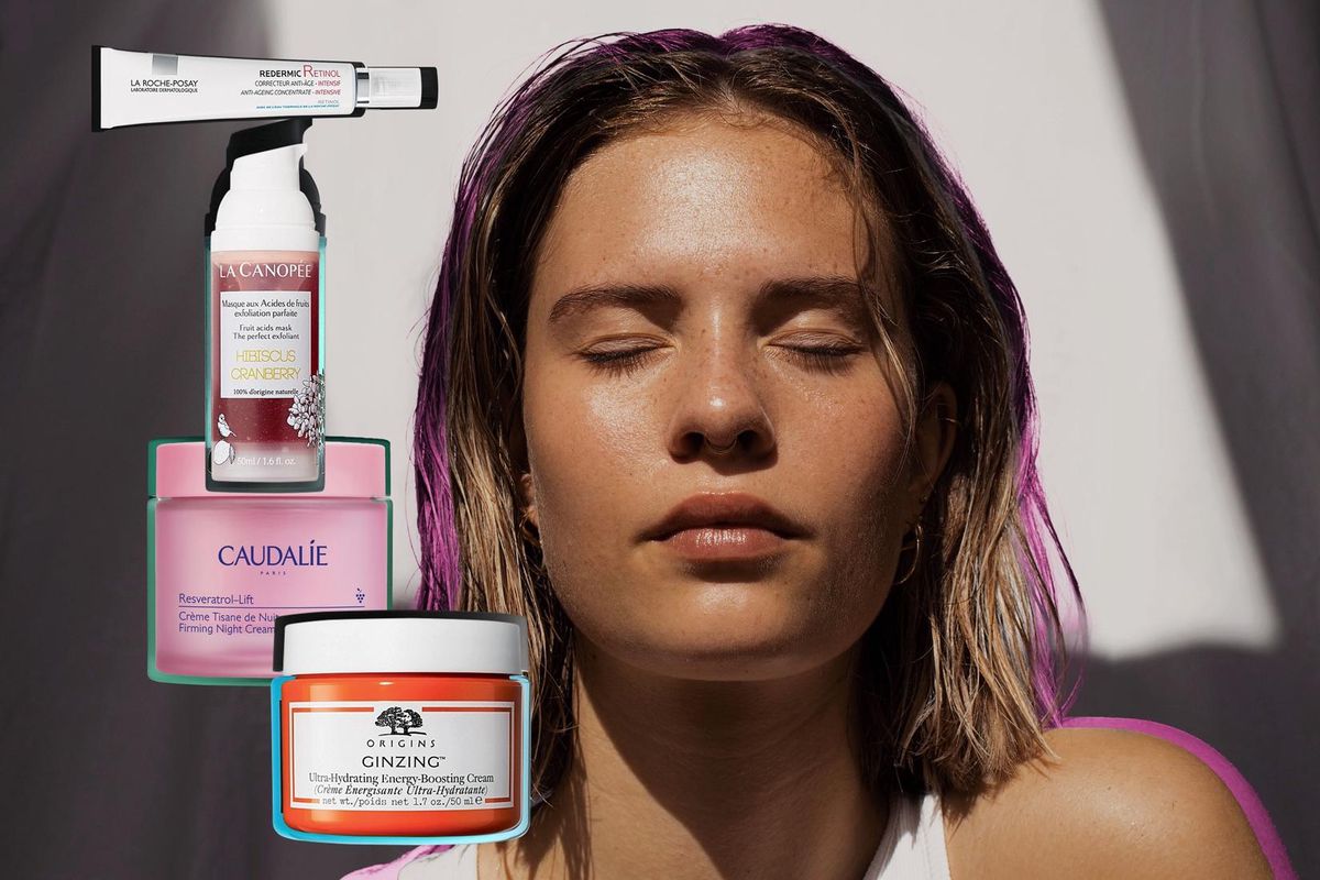 Jeune femme aux cheveux mouillés, yeux fermés, entourée de produits de soins de la peau, dont des crèmes et sérums.