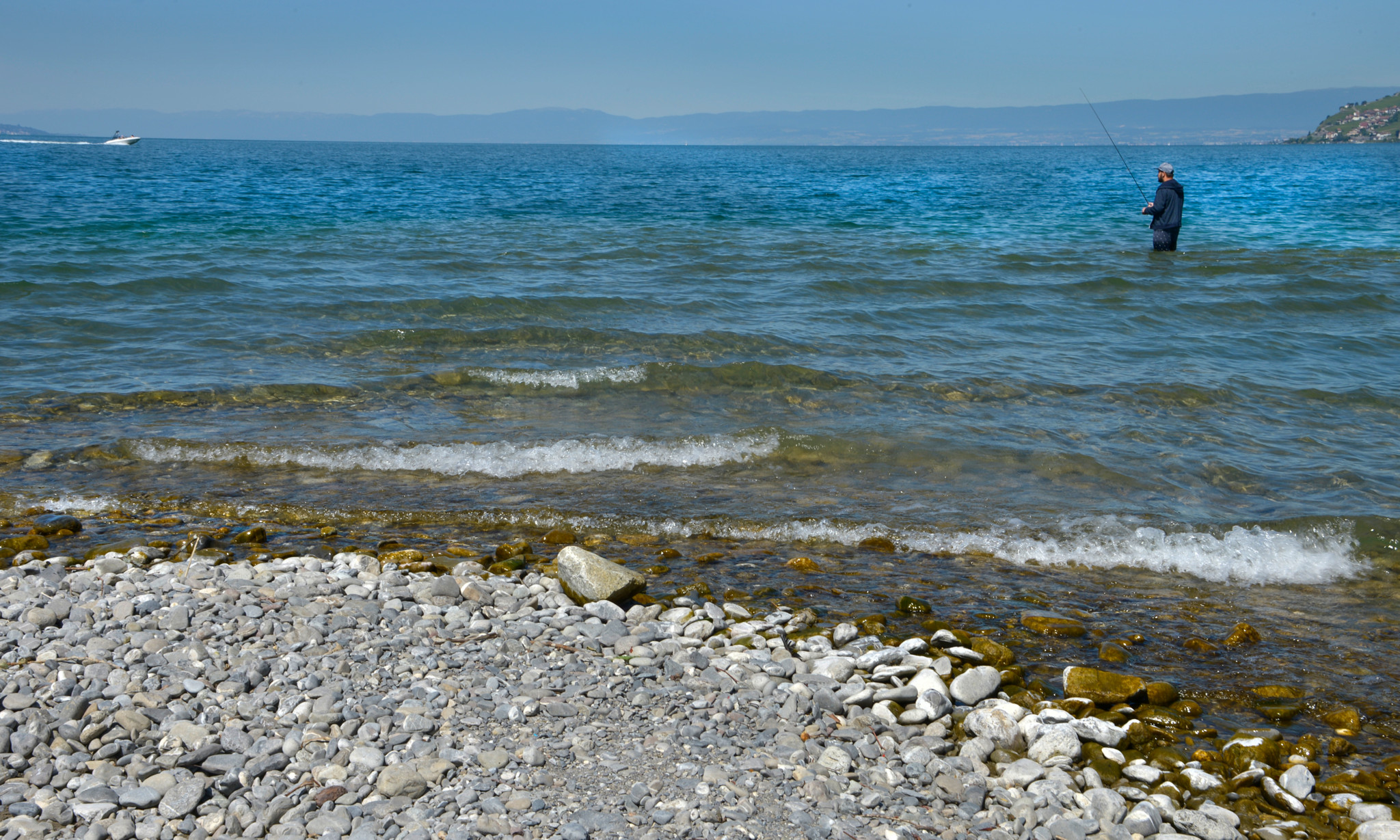 Kiesiger Uferbereich an der Mündung der Veveyse in den Genfersee bei Vevey, mit einer Person im flachen Wasser
