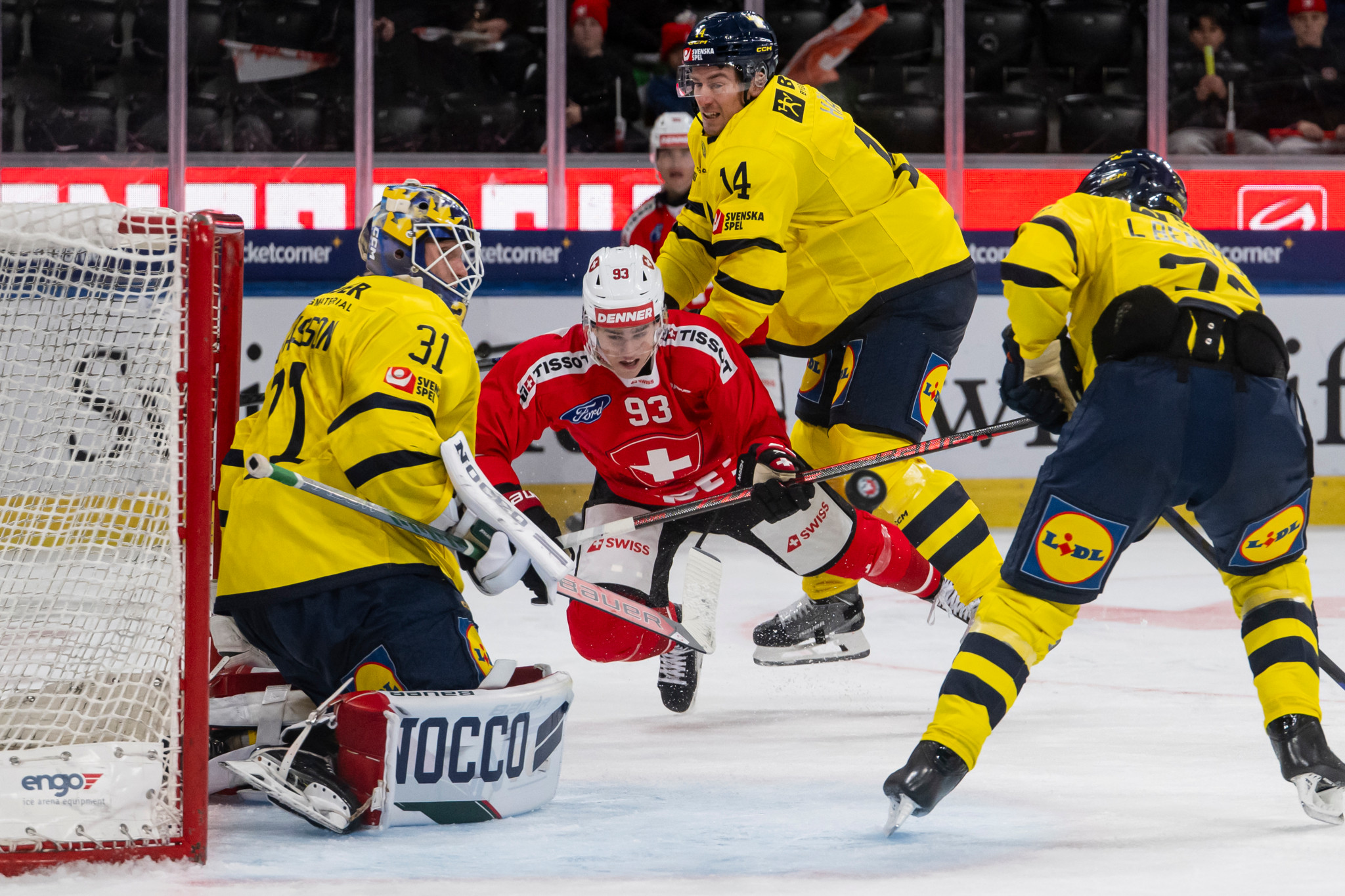 Le joueur suisse Theo Rochette lutte pour le palet contre le gardien suédois Lars Johansson, avec Robert Haegg et Lukas Bengtsson, lors du match de hockey entre la Suède et la Suisse à l'Euro Hockey Tour à Zurich, le 11 décembre 2025.