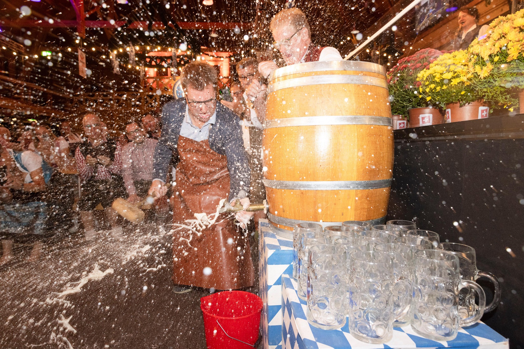 Toni Brunner zapft ein Bierfass am Oktoberfest Winterthur, umgeben von spritzendem Bier. Foto von Roger Hofstetter.