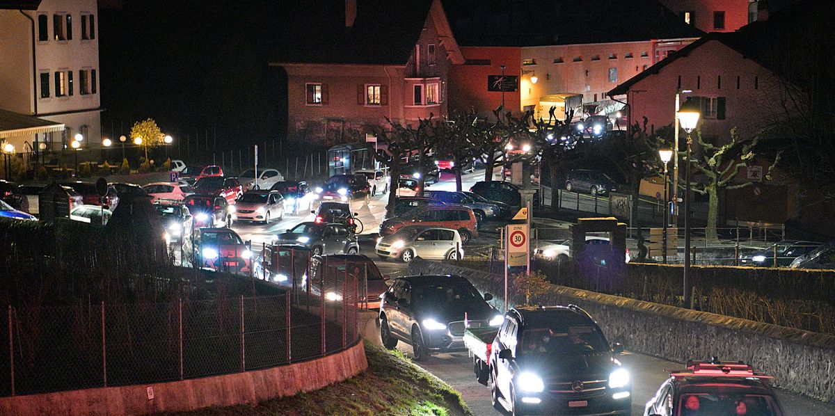 Embouteillage nocturne dans le village d'Yvorne causé par le retour du ski dimanche. Les voitures sont coincées sur les routes étroites, les phares illuminant la scène.