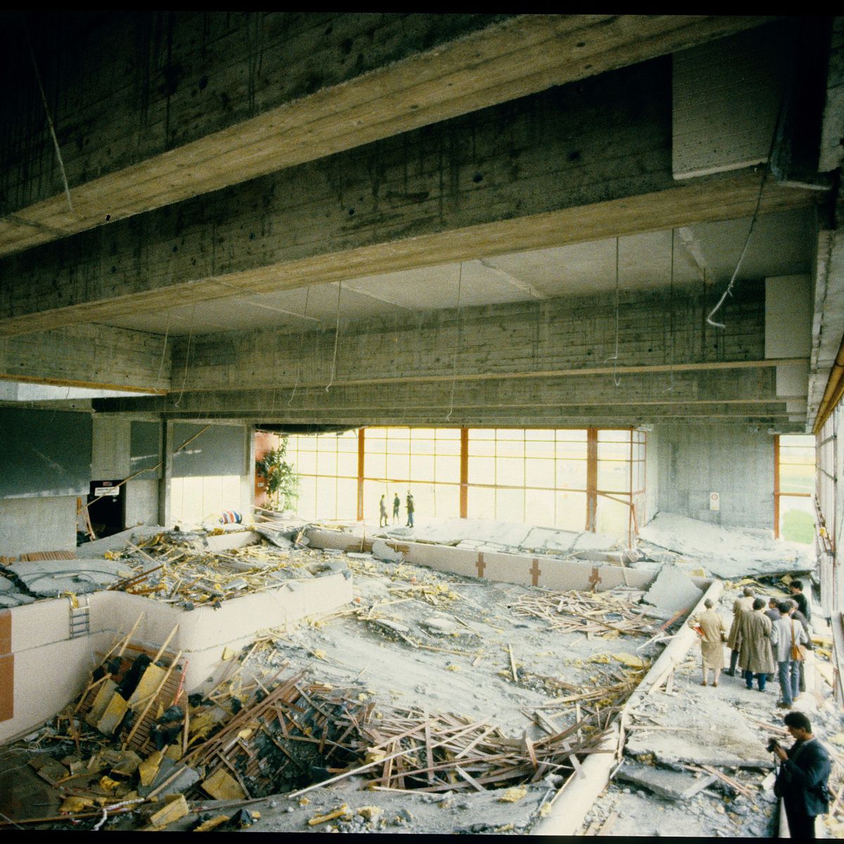 Decken-Einsturz im Hallenbad Uster 1985 mit Trümmern im Innenraum, mehrere Personen inspizieren die Schäden.
