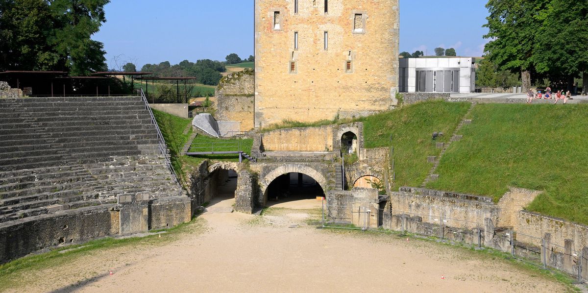Vue du Musée romain de Avenches avec l'amphithéâtre en pierres et une tour en arrière-plan sous un ciel bleu. Photo prise le 20 juillet 2024.