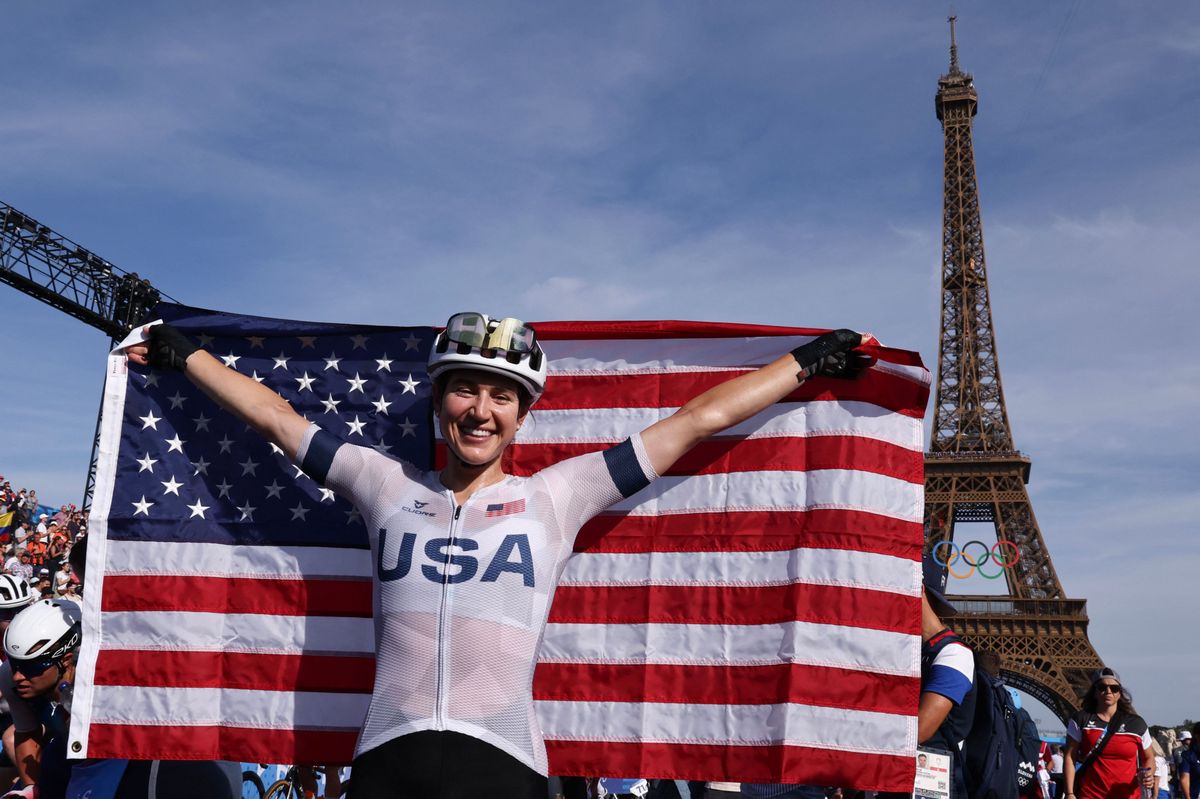 US' Kristen Faulkner celebrates her victory with a US flag in front of the Eiffel Tower after winning the women's cycling road race during the Paris 2024 Olympic Games in Paris, on August 4, 2024. (Photo by David GRAY / AFP)
