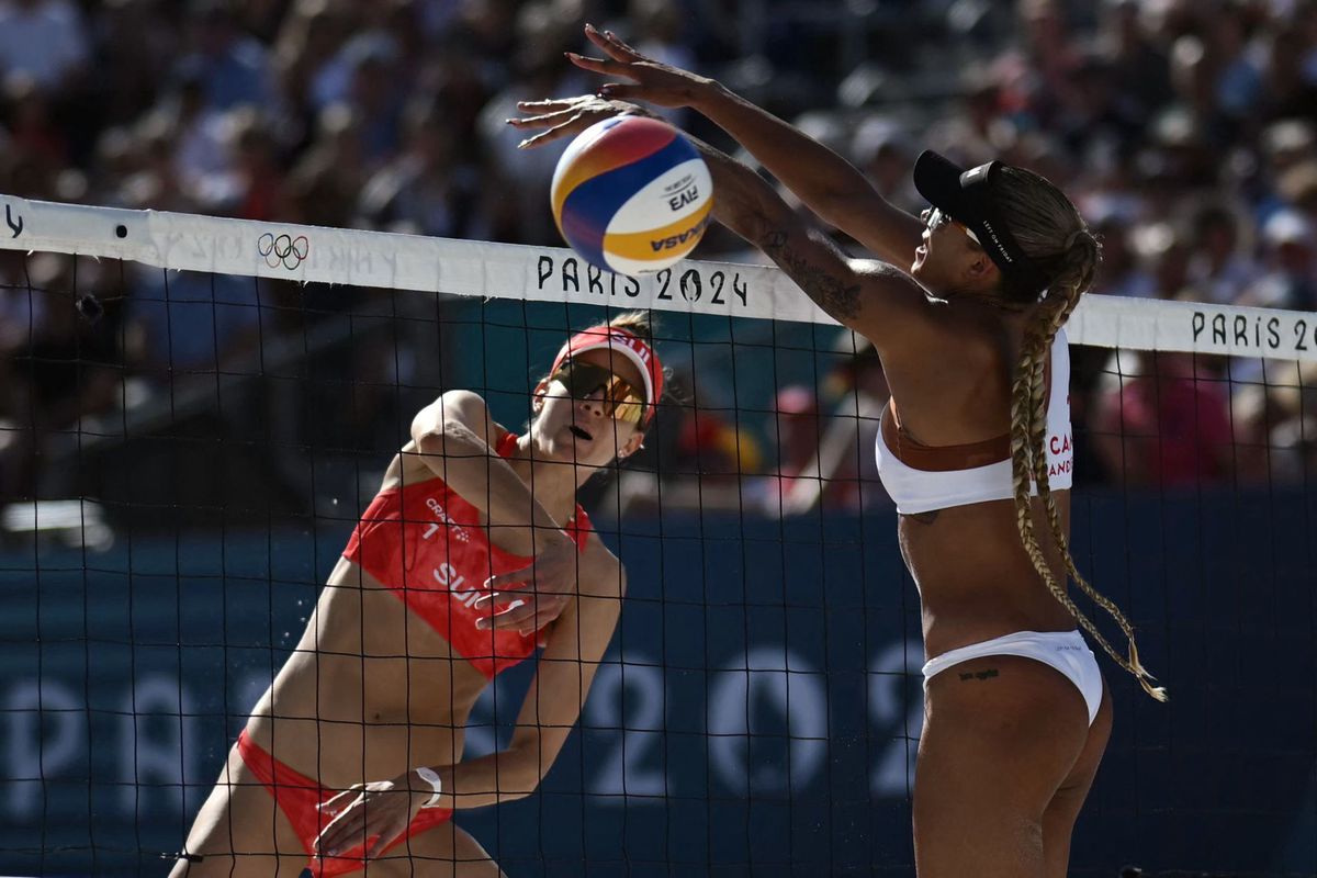 Switzerland's #01 Tanja Hueberli spikes the ball as Canada's #02 Brandie Wilkerson blocks in the women's semi-final beach volleyball match between Switzerland and Canada during the Paris 2024 Olympic Games at the Eiffel Tower Stadium in Paris on August 8, 2024. (Photo by CARL DE SOUZA / AFP)