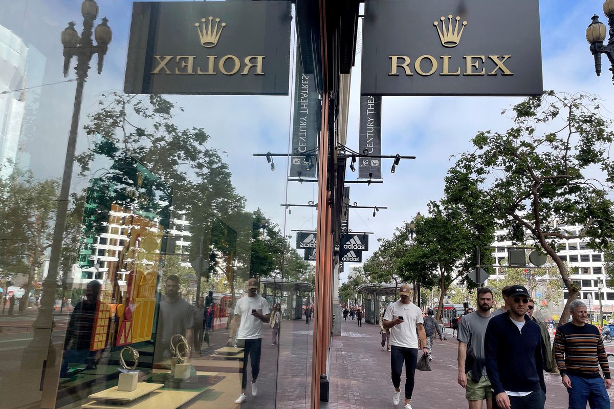 Vitrine de montres Rolex au Rolex Boutique Tourneau à San Francisco avec des passants reflétés dans la vitrine.