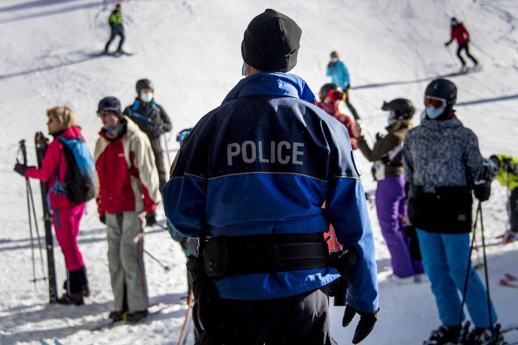Un policier à Verbier contrôlant le port du masque des skieurs, samedi 28 novembre 2020 (KEYSTONE/Jean-Christophe Bott)