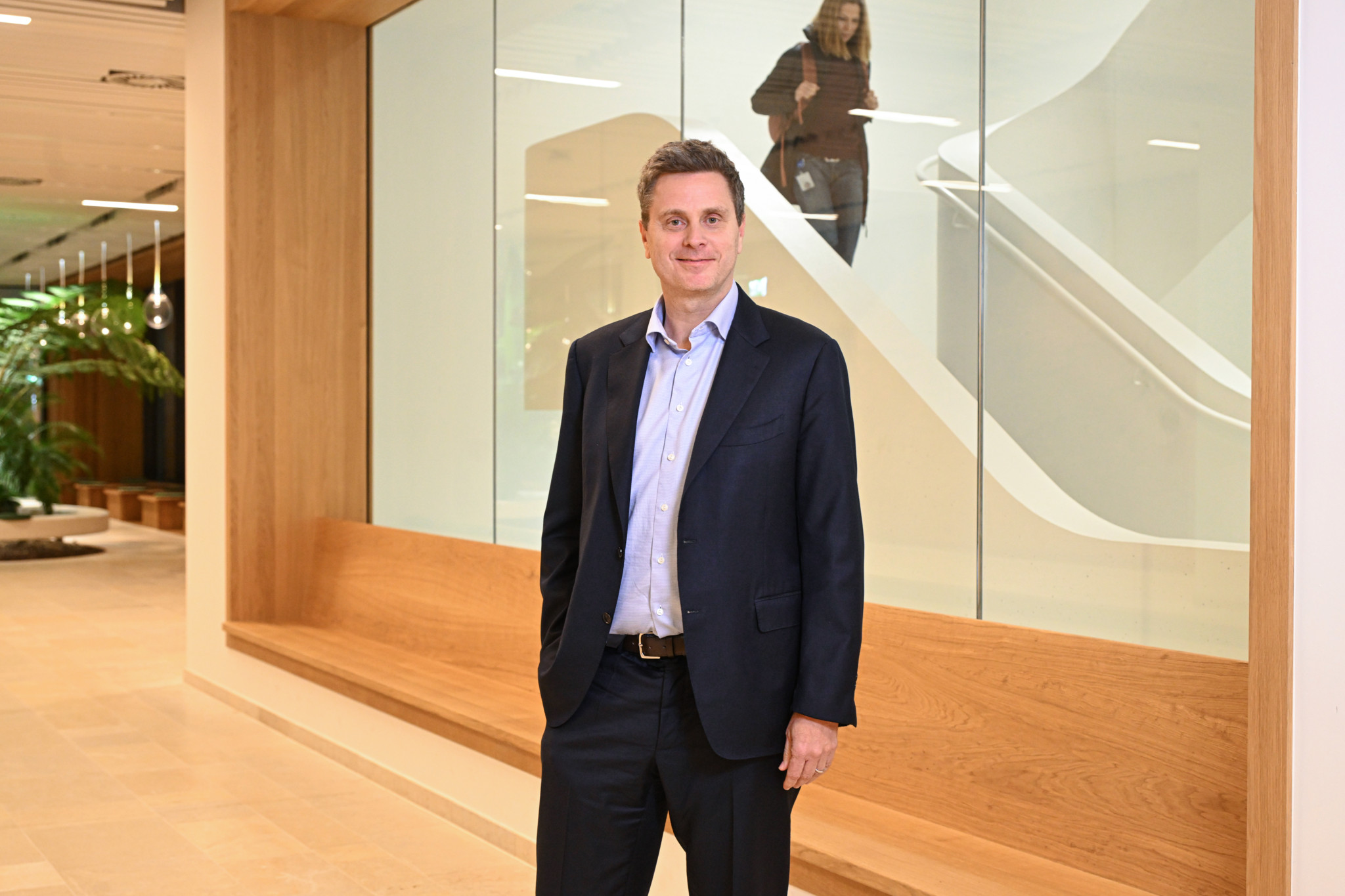Thomas Schinecker, der CEO von Roche, in einem modernen BÃ¼rogebÃ¤ude in Basel, mit einer Treppe im Hintergrund.