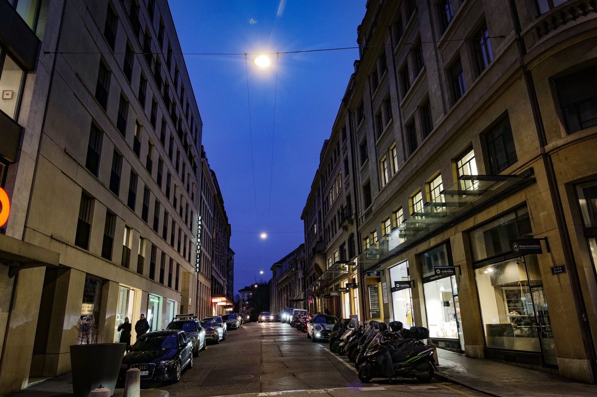 Rue de la Rôtisserie à Genève dans la soirée, avec des bâtiments éclairés et des voitures garées le long de la rue. Incident grave survenu le 25 février.