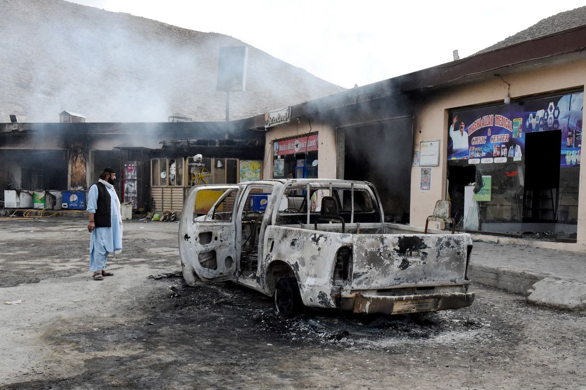 A man looks at charred shops and a vehicle torched by armed separatist group Balochistan Liberation Army (BLA) at central Bolan district in Balochistan province on January 30, 2024. At least six militants were killed in an overnight gun battle with security forces in western Pakistan's Balochistan province, an official said on January 30. (Photo by Banaras KHAN / AFP)
