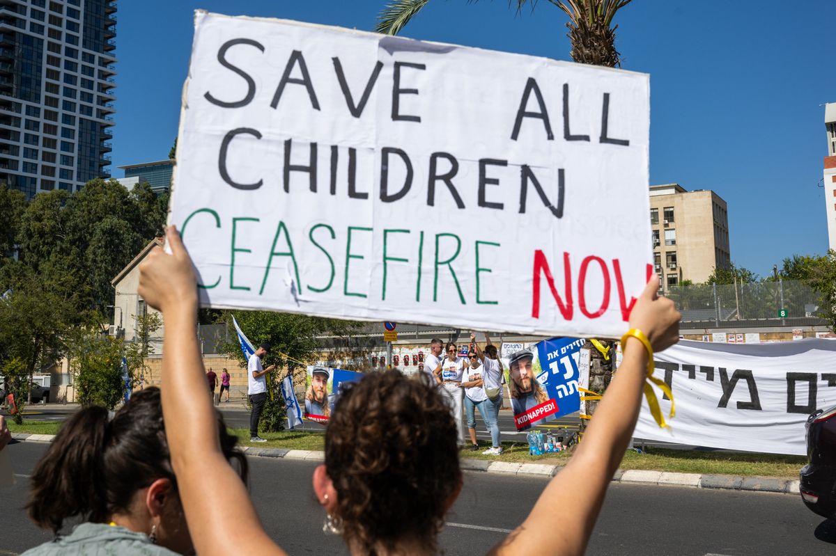 TEL AVIV, ISRAEL - OCTOBER 20: A woman holds a "save all children, ceasefire now" sign near demonstrators holding signs of the people kidnapped outside HaKirya, The Kirya, on October 20, 2023 in Tel Aviv, Israel. As Israel prepares to invade the Gaza Strip in its campaign to vanquish Hamas, the Palestinian militant group that launched a deadly attack in southern Israel on October 7th, worries are growing of a wider war with multiple fronts, including at the country's northern border with Lebanon. Countries have scrambled to evacuate their citizens from Israel, and Israel has begun relocating residents some communities on its northern border. Meanwhile, hundreds of thousands of residents of northern Gaza have fled to the southern part of the territory, following Israel's vow to launch a ground invasion. (Photo by Alexi J. Rosenfeld/Getty Images)