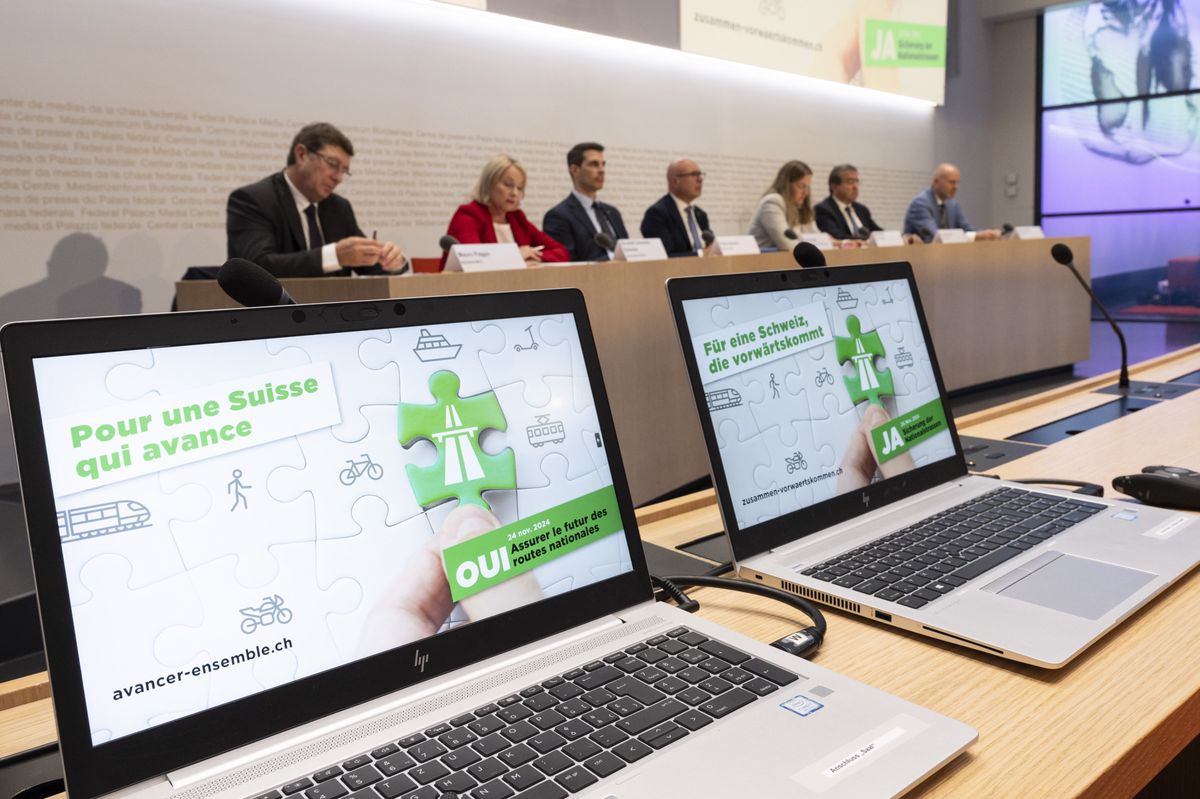 Conférence de presse du comité 'Oui à la sécurisation des routes nationales' à Berne, le 24 septembre 2024. Des membres du comité, comprenant Mauro Poggia, Elisabeth Schneider-Schneiter, Thierry Burkart, Fabio Regazzi, Katja Riem, Pascal Broulis, et Thomas Hurter, sont assis à une table devant des ordinateurs affichant des messages de soutien.