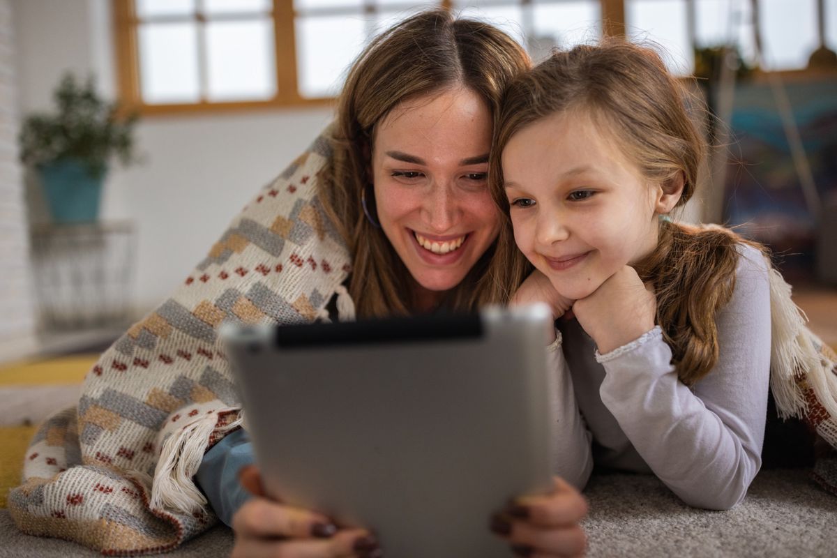 Caucasian mother and daughter watching movie or having a video call on digital tablet