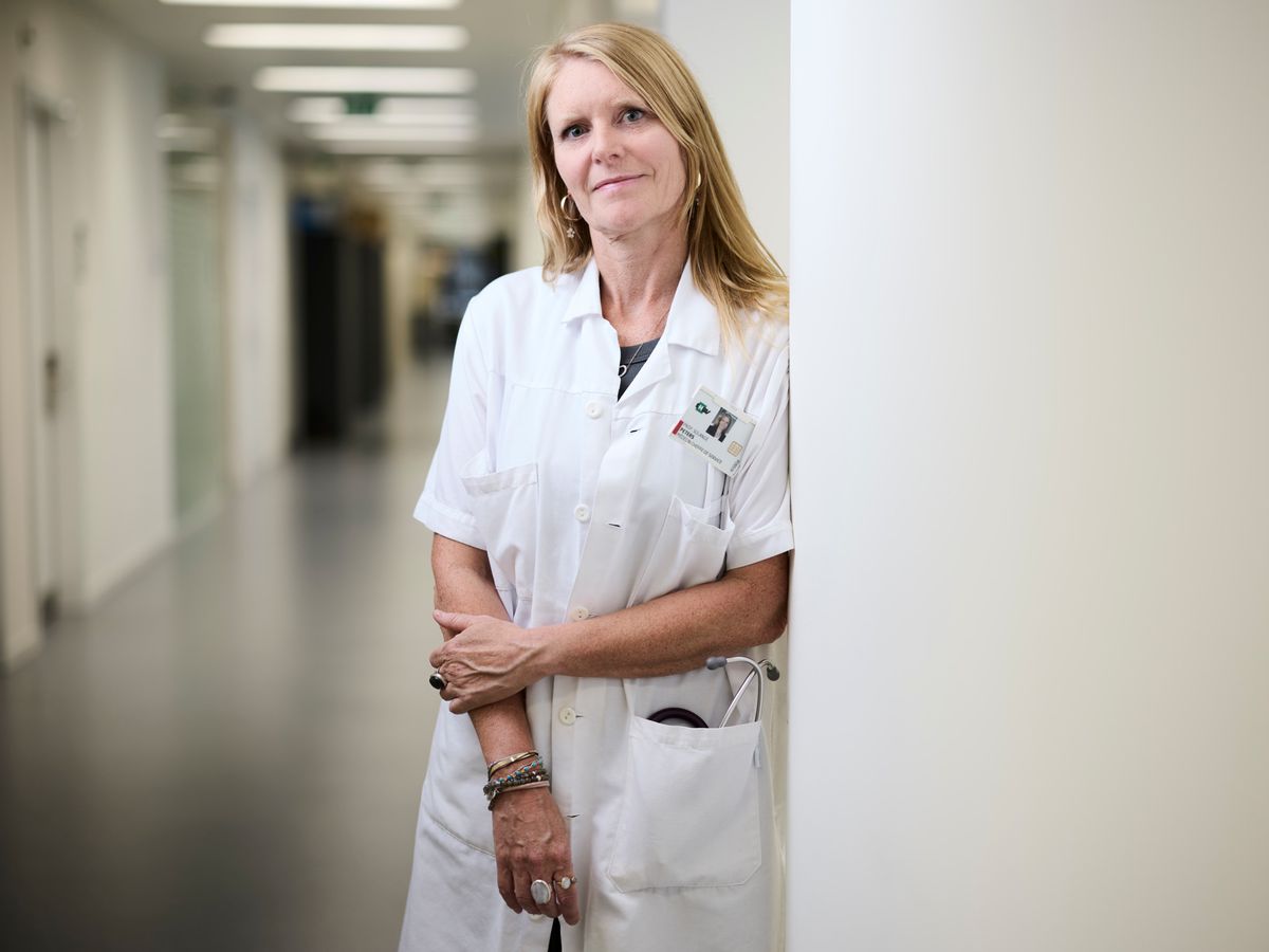 Portrait de la Professeur Solange Peters, Cheffe du service d’oncologie médicale du CHUV, prise le 15 août 2024 à Lausanne. Elle porte une blouse blanche et se trouve dans un couloir de l'hôpital.