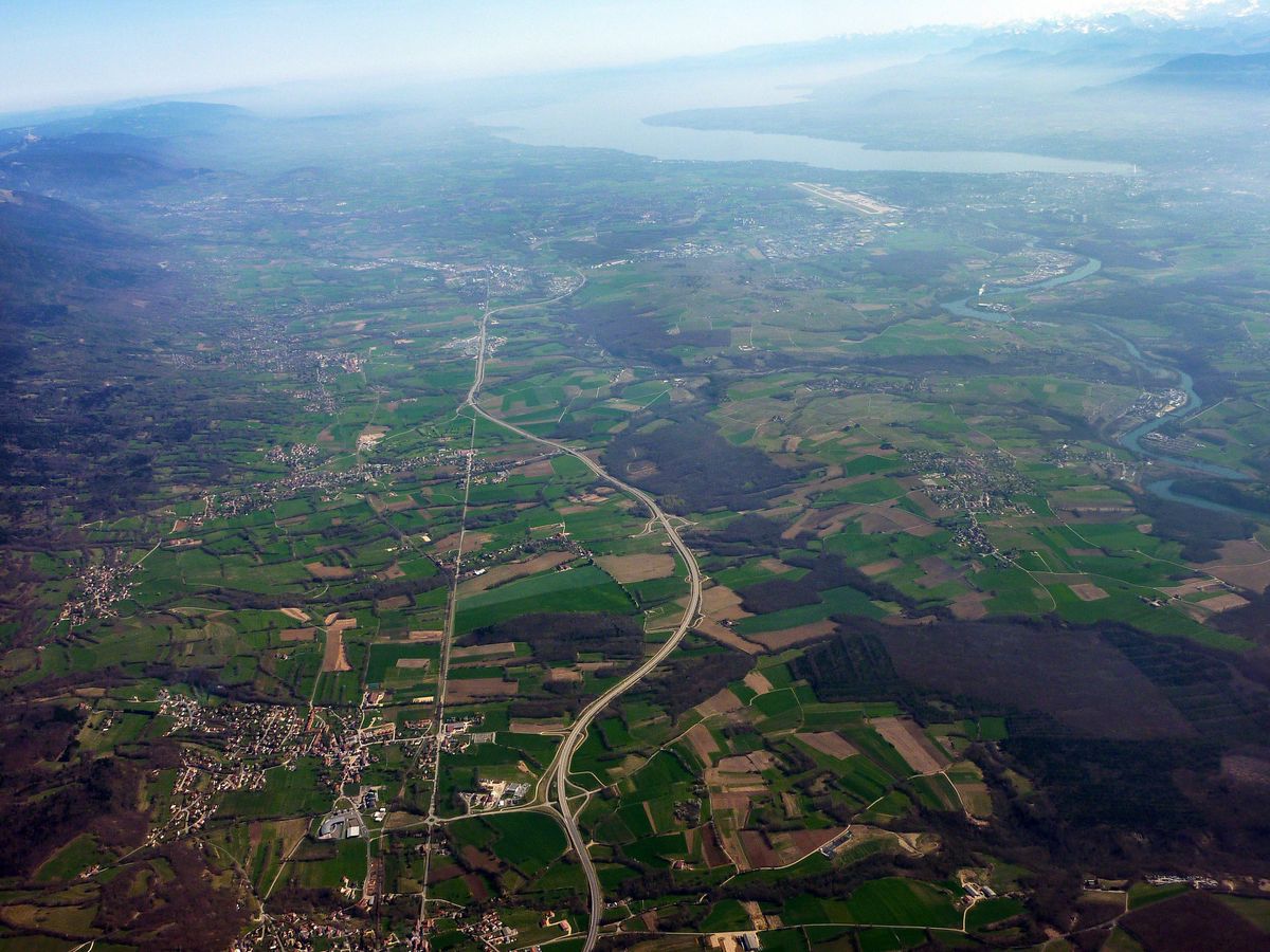 Vue aérienne du Pays de Gex avec la voie rapide D884, Genève et le lac Léman en arrière-plan.