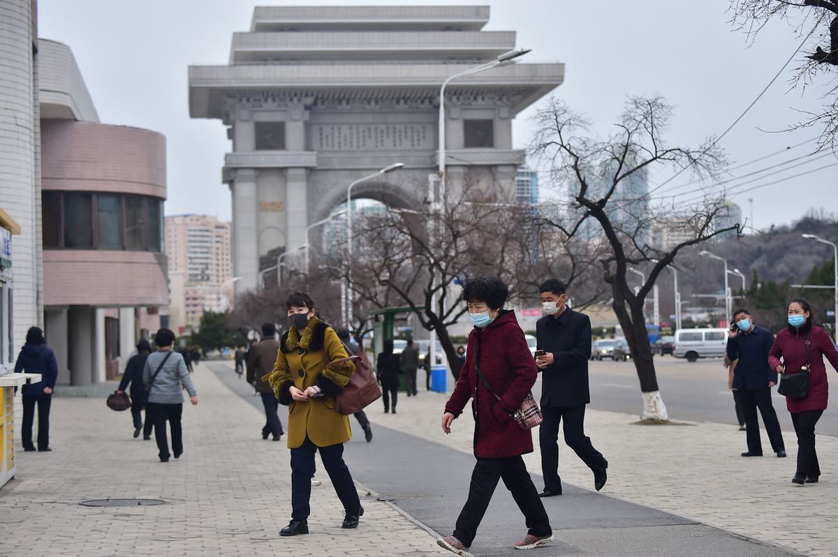 People walk along a street in front of the Arch of Triumph in Pyongyang on March 25, 2024. (Photo by KIM Won Jin / AFP)