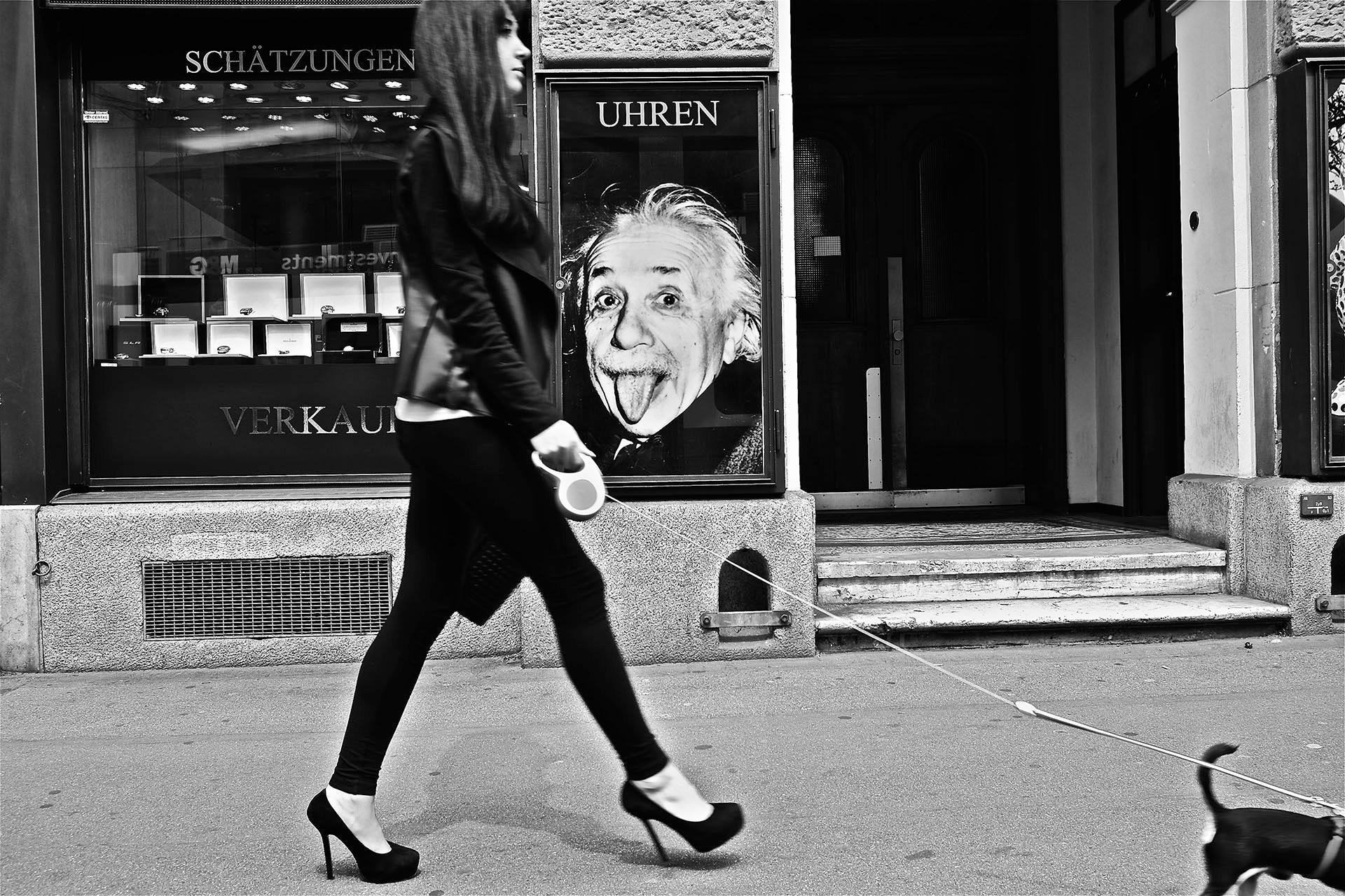 Frau spaziert mit Hund an Einstein-Plakat vorbei