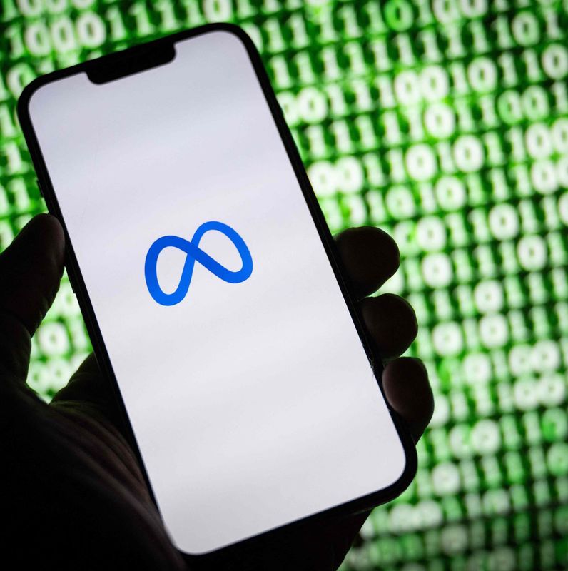 Logo de Meta affiché sur un smartphone devant un écran de code binaire, Mulhouse, octobre 2023.