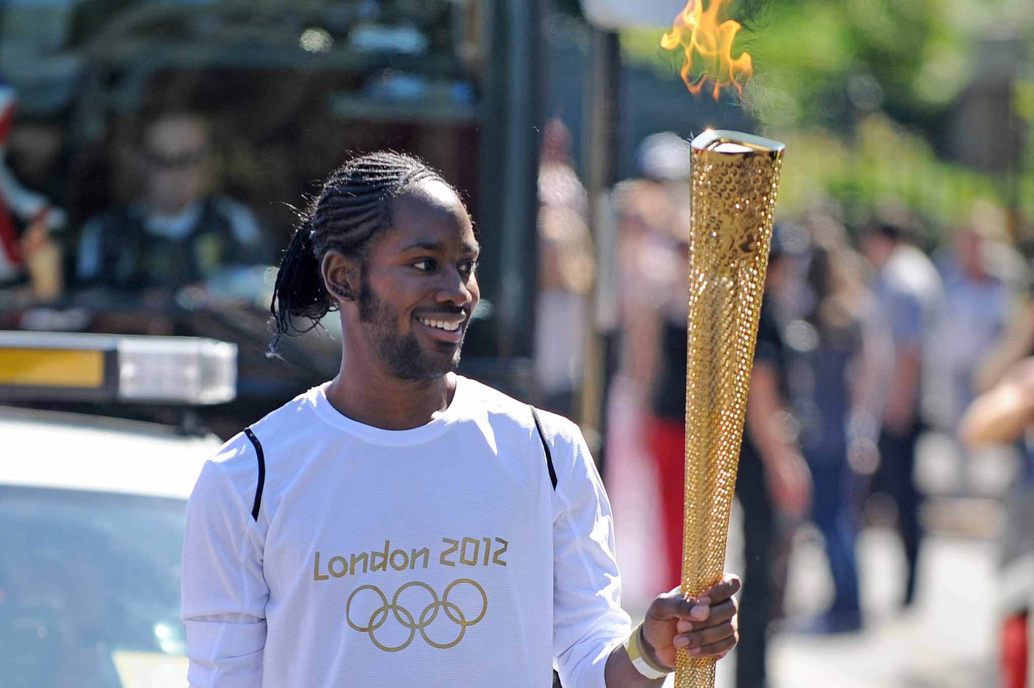 Fackelträger Jason Arday trägt die Olympische Flamme beim Fackellauf in London, Juli 2012, mit der Aufschrift «London 2012» auf seinem Trikot.