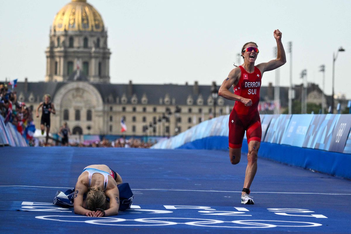 France's Cassandre Beaugrand (L) reacts after crossing first next to Switzerland's Julie Derron on the Pont Alexandre III at the end of the women's individual triathlon race at the Paris 2024 Olympic Games in central Paris, on July 31, 2024. (Photo by Jeff PACHOUD / AFP)
