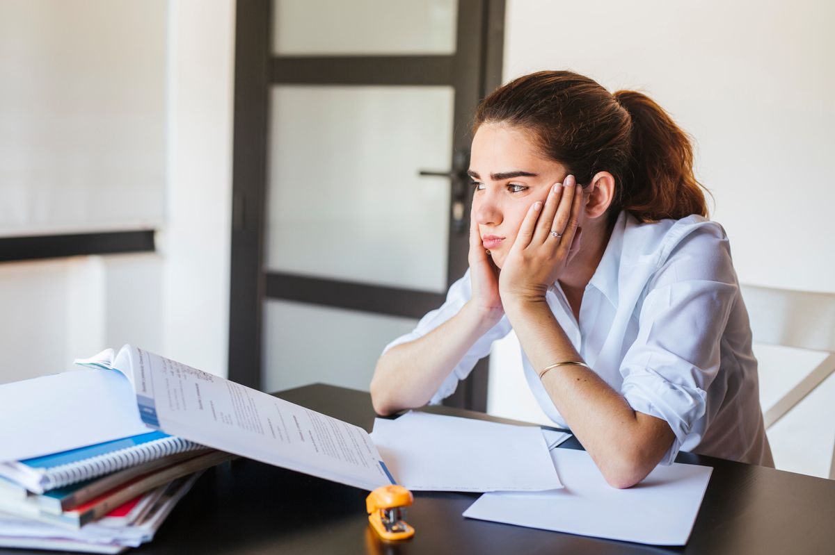 Frustrated female student with documents at desk at home