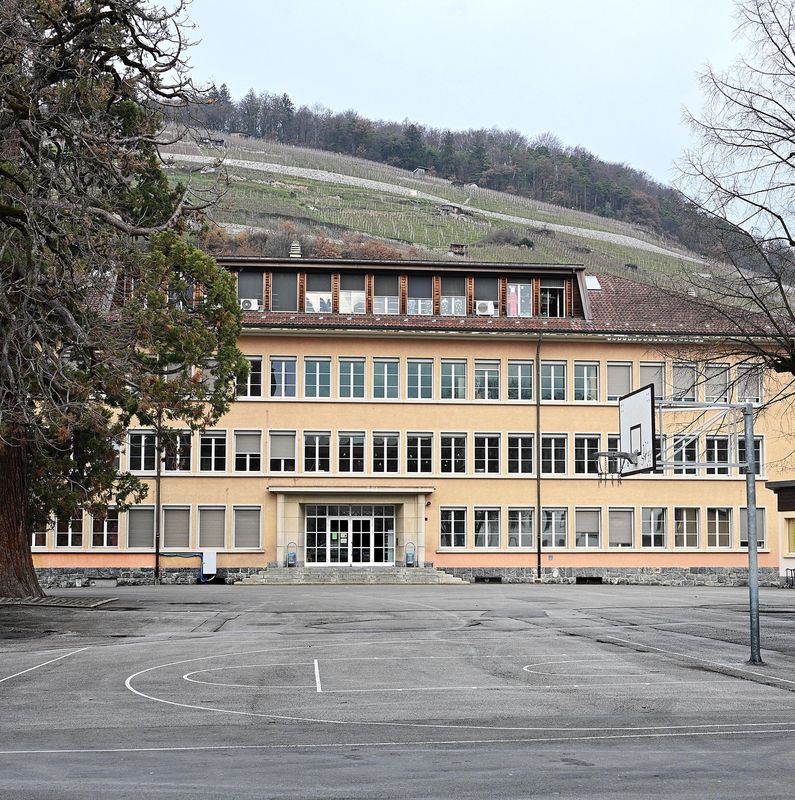 Bâtiment principal de l’école de Bex avec un terrain de basketball devant, situé au chemin du Pré de la cible.