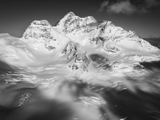 Montagne enneigée majestueuse vue du ciel avec ombres et textures sur la neige et les sommets.