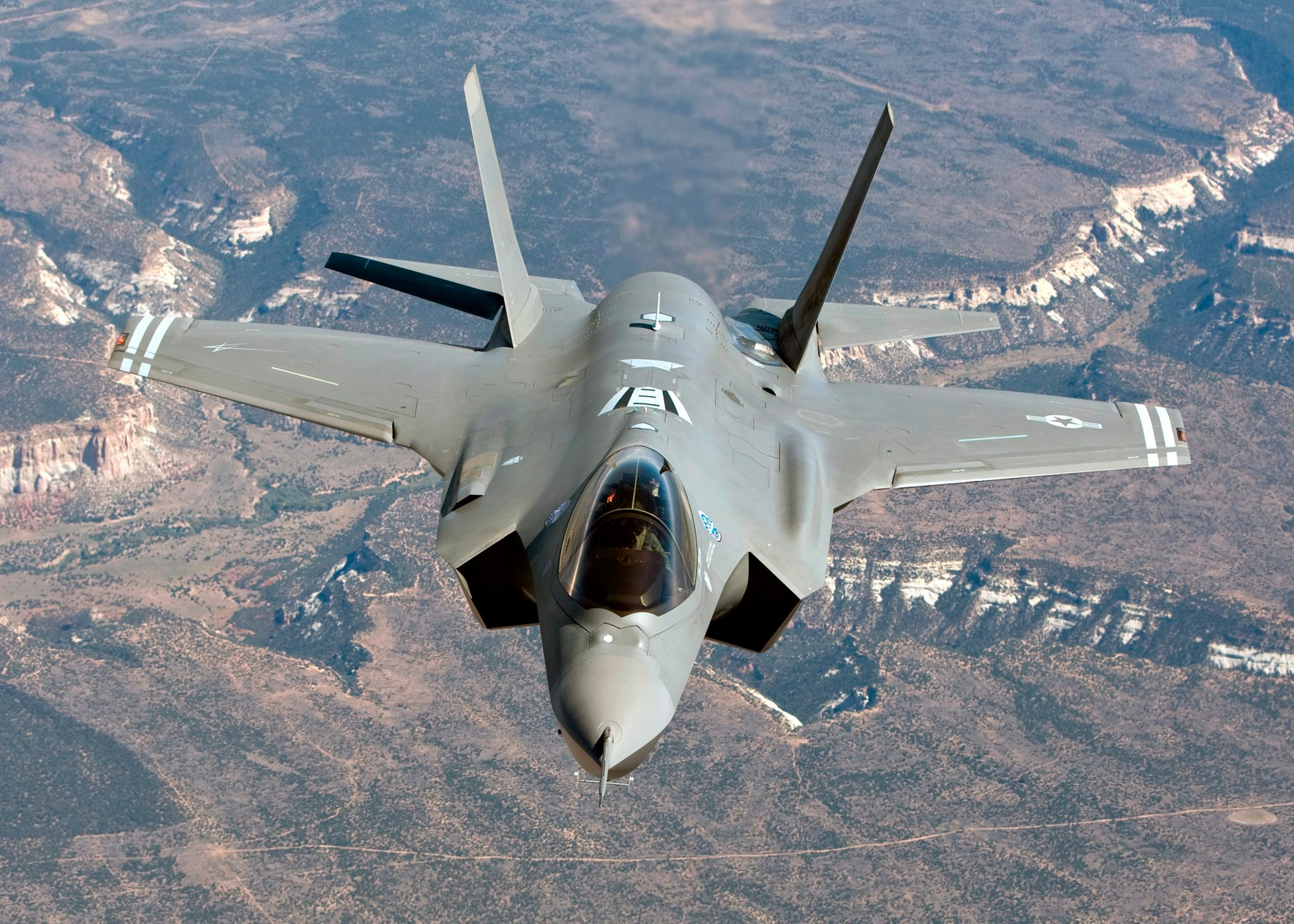 Ein F-35A-Kampfjet fliegt über eine Landschaft aus der Vogelperspektive.
