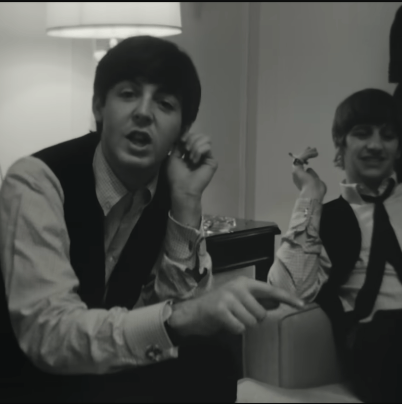 Deux musiciens assis dans une pièce, discutant. L’un pointe vers l’avant, l’autre sourit avec une cigarette à la main. Logo Disney+ en haut à droite.